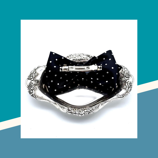 Black polka dot bow on a decorative silver tray with a blue and white geometric background